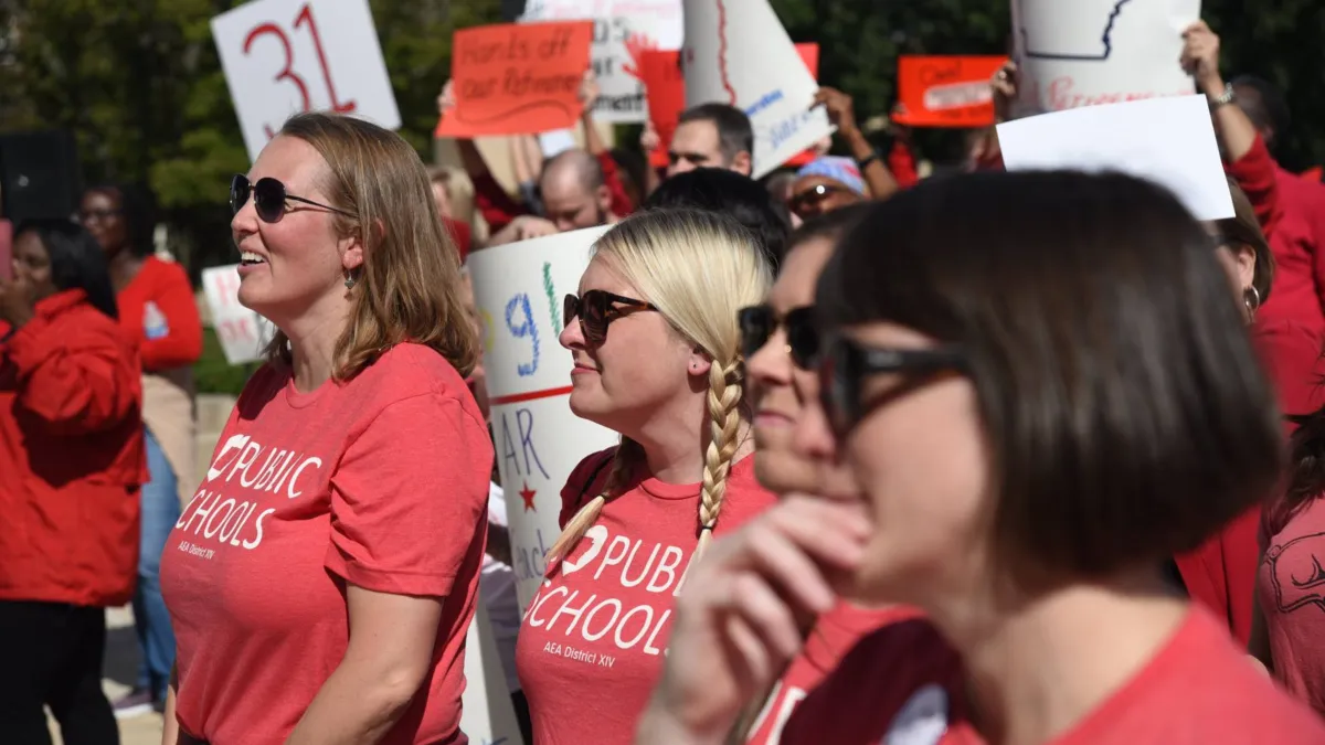 AEA members dressed in a crowd at a statehouse rally listening to speakers.