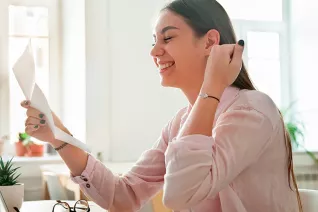 A woman grinning holding a piece of paper