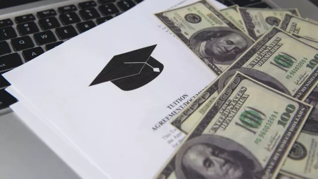 hundred dollar bills on top of a tuition agreement
