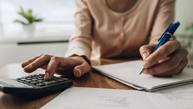a woman working with a calculator and pen and paper