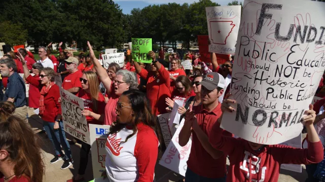 2018 rally - educators in red with signs that read "protect our students' future," "stand up for students," etc.