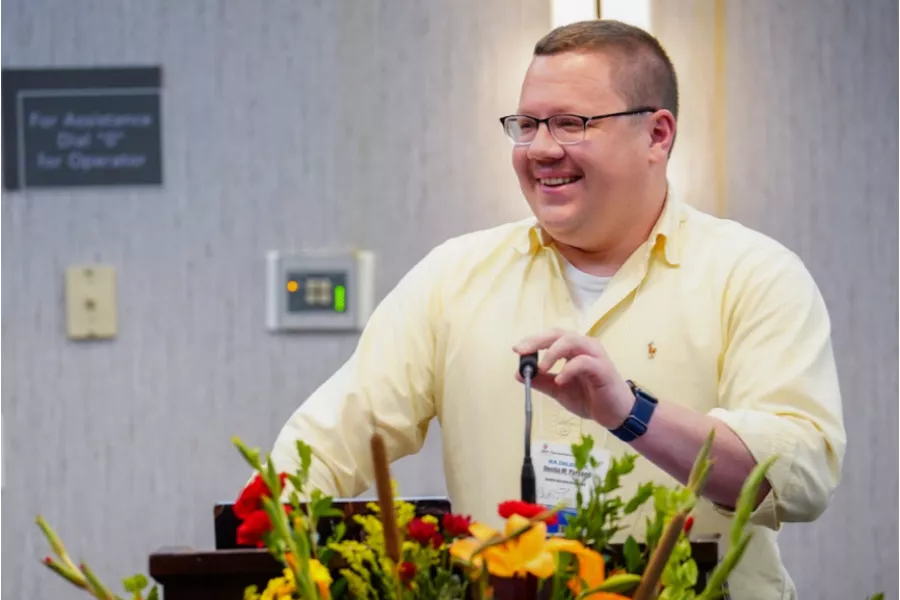 an educator at a microphone with flowers in front
